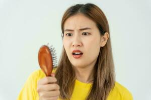 Asian woman very sad and upset looking at damaged hair, hair loss, hair thinning problem, vitamin deficiency, baldness, postpartum, biotin, zinc, menstrual or endocrine disorders, hormonal imbalance photo