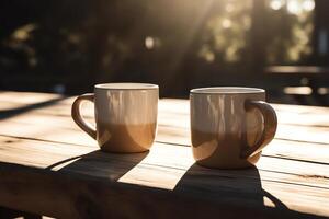 Two coffee mugs sitting on a wooden table outside on a sunny day with trees in the backgroup of the picture and a blurry background. photo