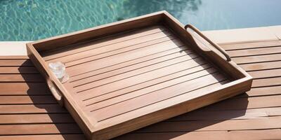 A wooden tray on a wooden deck next to swimming pool photo