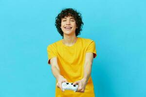 gamer plays with joystick in yellow t-shirts blue background photo