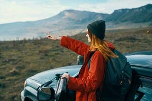 woman hiker in the mountains on nature near the car with a backpack on the back photo