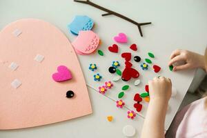 A blogger girl makes a felt craft for Valentine's Day in the shape of a heart. The concept of children's creativity and handmade. photo