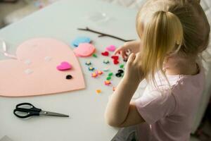 un blogger niña hace un sintió arte para San Valentín día en el forma de un corazón. el concepto de para niños creatividad y hecho a mano. foto