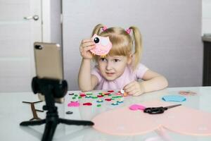 A blogger girl makes a felt craft for Valentine's Day in the shape of a heart. The concept of children's creativity and handmade. photo