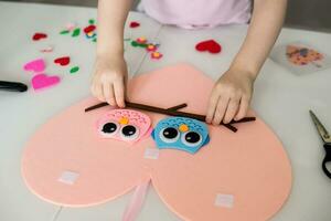 A blogger girl makes a felt craft for Valentine's Day in the shape of a heart. The concept of children's creativity and handmade. photo