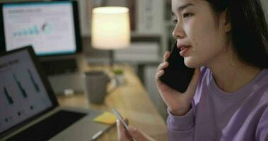 beeldmateriaal van jong Aziatisch vrouw, freelance bedrijf analist pratend Aan mobiel telefoon Bij huis. telewerken en levensstijl concepten. video