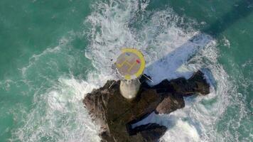 Leuchtturm auf ein Felsen im das Meer mit abstürzen Wellen und ein Hubschrauberlandeplatz video