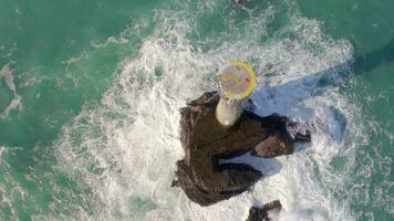 Leuchtturm auf ein Felsen im das Meer mit abstürzen Wellen und ein Hubschrauberlandeplatz video