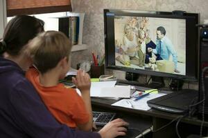 A woman and a child are sitting at a table and talking via video link with relatives or friends. Staying at home, quarantine and social distancing during the New Years. photo