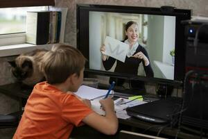 The student is talking via video link with the teacher at the computer. Online education and e-learning concept. Home quarantine, distance learning and work from home. photo