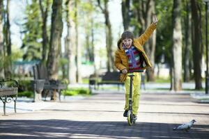 chico contento en un scooter en un ciudad parque. foto