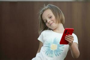 niño con un teléfono inteligente gracioso pequeño niña bailando con un rojo teléfono. foto