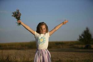 Beautiful little girl in the meadow with a bouquet of flowers. A child in a beautiful summer field. photo