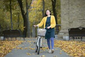 Middle-aged woman with a bicycle in an autumn park. photo