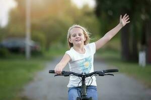 un niña con largo pelo paseos un bicicleta en un verano día. foto