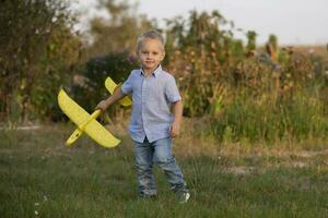 pequeño chico en el campo obras de teatro con un avión. foto