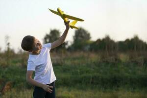 Little boy in the field plays with a yellow plane. photo