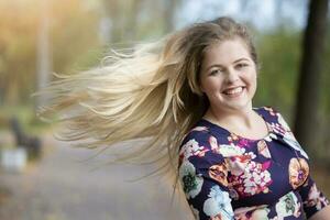 Beautiful blonde girl with long developing hair in the park. photo