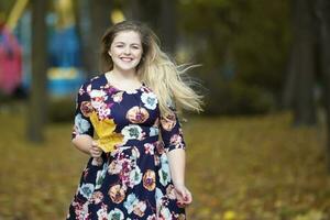 Happy blonde girl in autumn park with maple leaves. photo