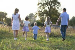 Happy family  mother, father, children, son and daughters in nature at sunset. Parents and children are walking together. The large family. photo