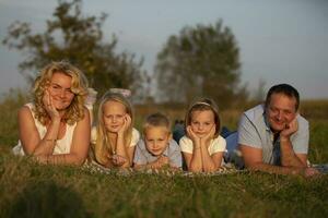 contento familia madre, padre, niños, hijo y hijas en naturaleza. un hermosa familia mentiras en el césped en el parque. foto