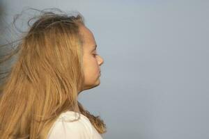 Little blonde girl in profile close-up on a background of blue sky. photo