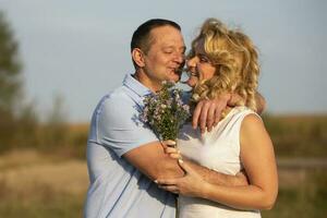 Beautiful middle-aged couple in love hugging on the background of nature. photo