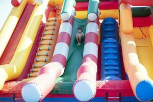 The boy slides down the inflatable slide. photo