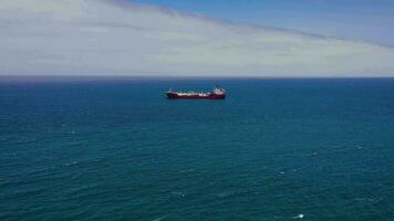 aéreo ver de un mar buque para transporte de un cargo seco Embarcacion con un cerrado sostener es anclado cerca el puerto marítimo ciudad y espera descarga. importar y exportar por mar. suave agua y claro cielo video