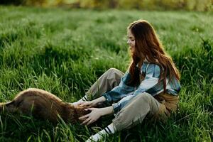 Woman game with her dog in nature smiling and lying on the green grass in the park, happy healthy relationship between mistress and pet photo