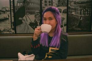 A woman with purple hair is drinking tea photo