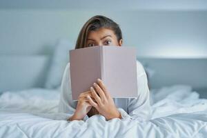 Brunette woman on bad with notepad or book photo