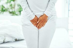 Young brunet woman with menstrual pain over bright bed photo