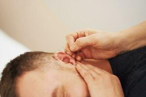 A picture of a man having acupuncture on ear photo