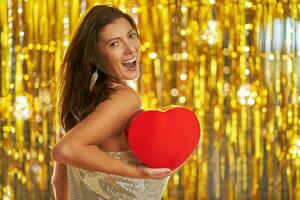 Young woman with heart over gold background photo