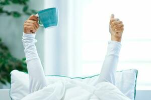 Young nice woman in bed with coffee or tea mug photo