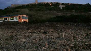 Train Moving On The Railway From The Train Station Near Obidos Castle In Portugal At Dusk - low angle, static drone video