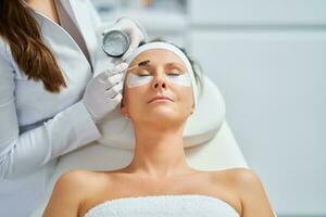 Woman having cosmetology eyebrows treatment in beauty salon photo