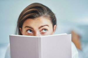 Brunette woman on bad with notepad or book photo