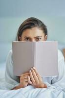 Brunette woman on bad with notepad or book photo