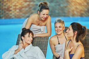 Group of girls on sunbed in front of pool photo