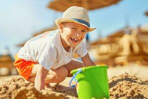 Image of a young boy playing with sand on the beach photo