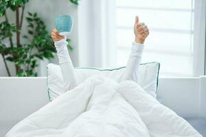 Young nice woman in bed with coffee or tea mug photo