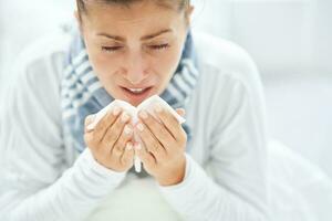 Young brunet woman sick in the bed with tissue photo