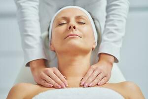 Young nice woman having face massage in spa photo