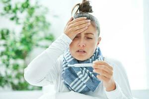 Young brunet woman sick in the bed with thermometer photo