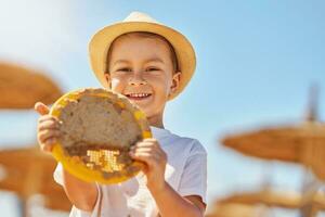 Image of a young boy playing with sand on the beach photo