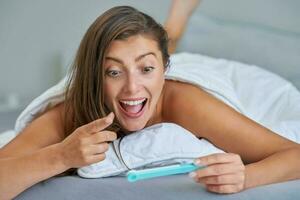 Young brunette woman with pregnancy test in the bed photo