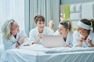 Group of girl friends at hotel spa party with laptop photo