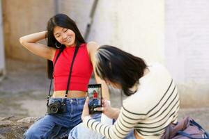 hembra asiático turistas tomando foto cerca ladrillo edificio